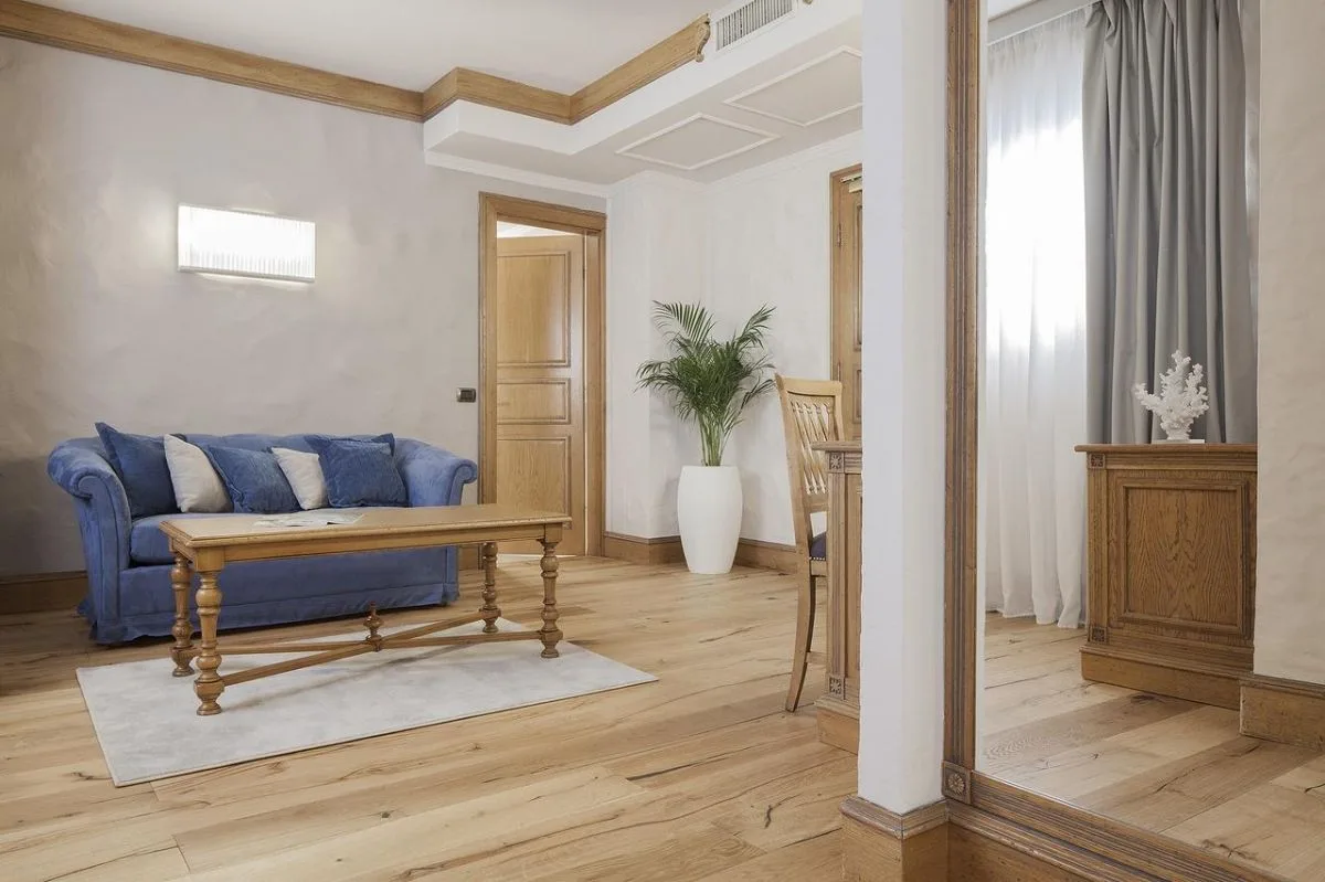 Soggiorno di suite con divano blu, tavolino in legno e pavimento in parquet