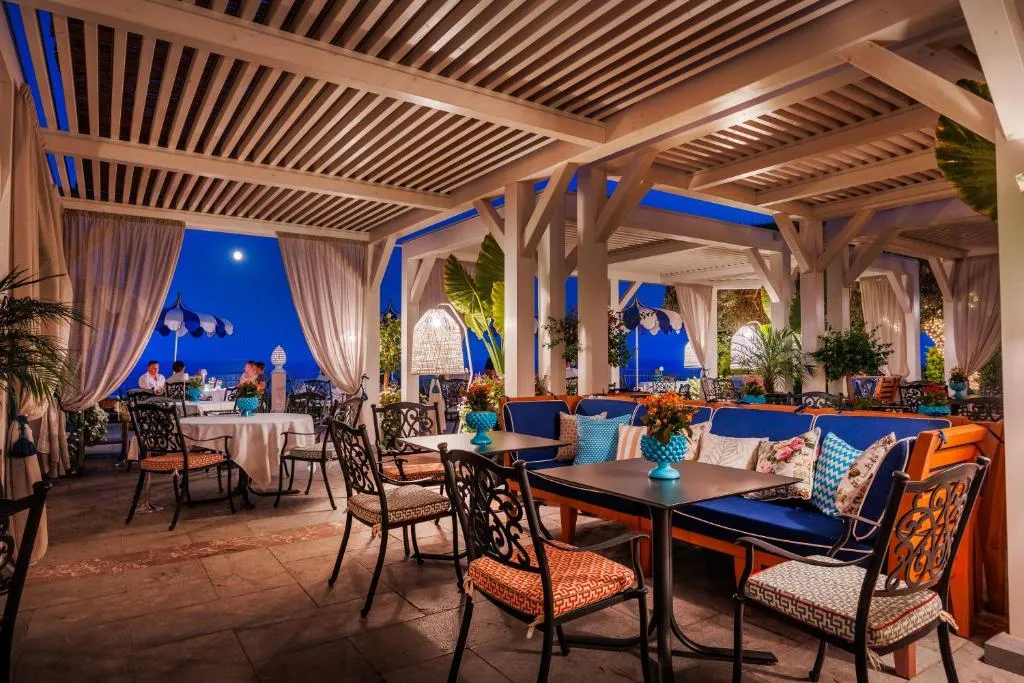 Ristorante coperto con pergolato illuminato di sera e vista sul mare