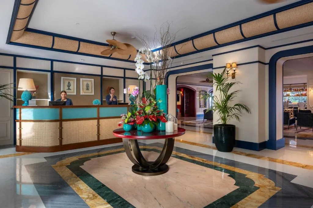 Reception dell'hotel con banco, composizione floreale e pavimento in marmo