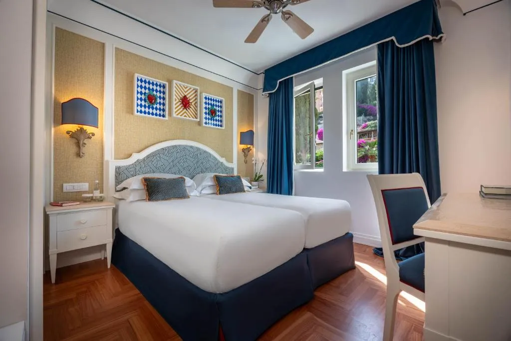 Camera con letto matrimoniale, testiera decorata e finestra con tende blu