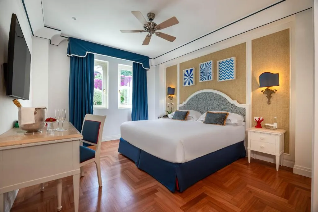 Camera luminosa con letto matrimoniale, scrivania e arredi bianchi e blu
