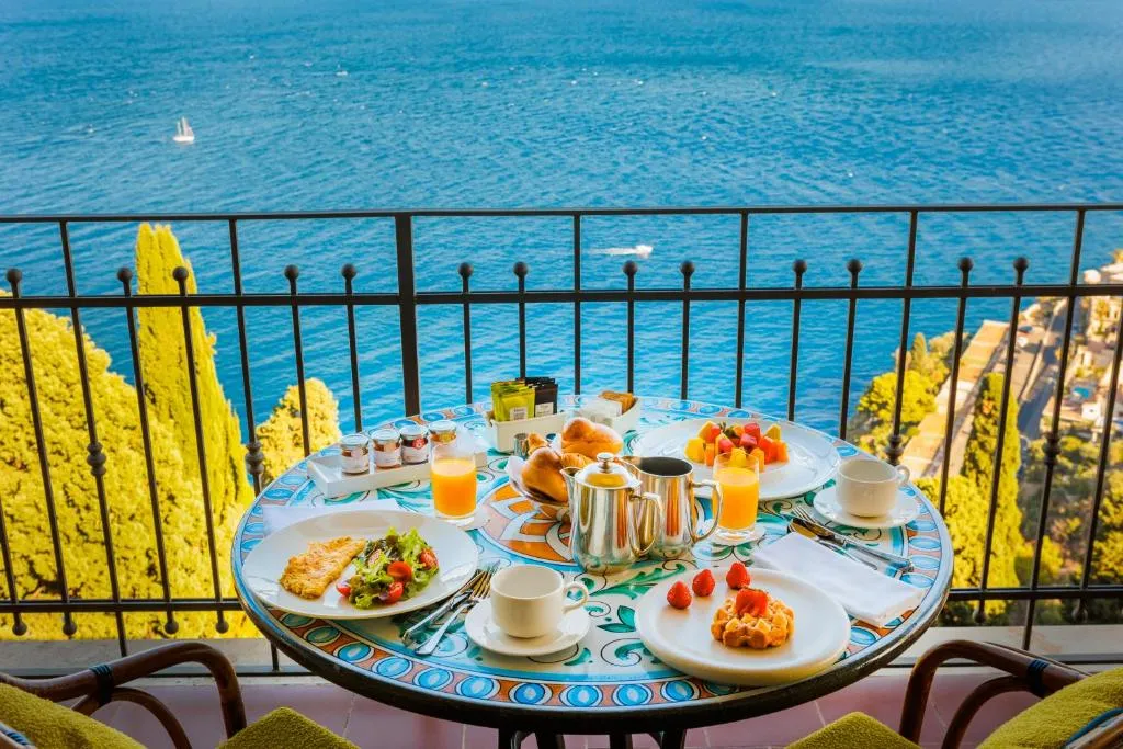 Colazione servita su tavolo in balcone con vista sul mare