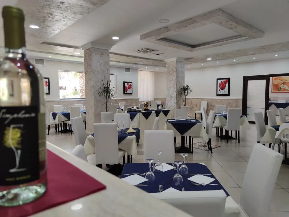 Sala ristorante con tavoli apparecchiati, tovaglie blu e sedie bianche