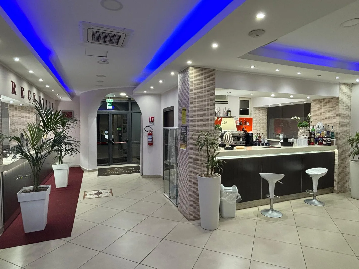 Hall dell'hotel con reception, bar e illuminazione blu a soffitto