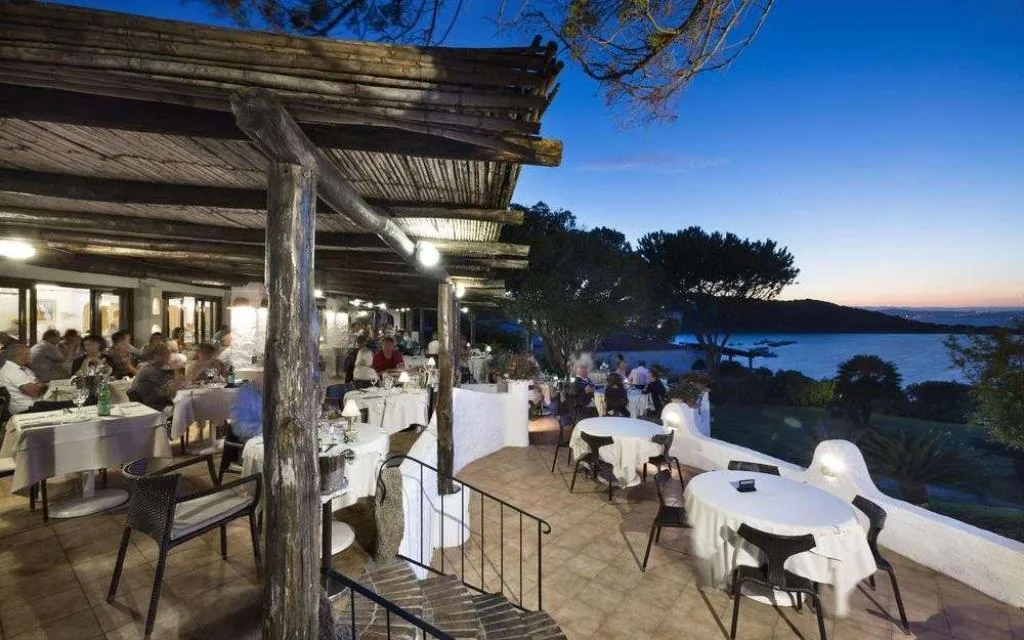 Terrazza ristorante illuminata di sera con vista sul mare al tramonto