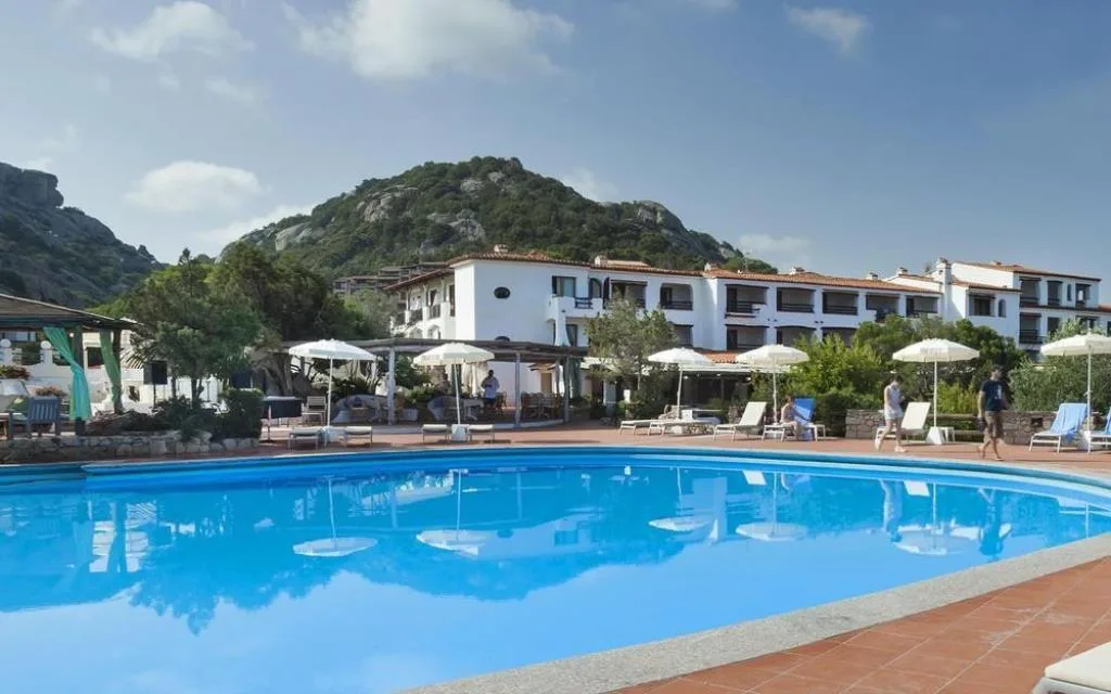 Piscina esterna dell'hotel con ombrelloni e vista sulle montagne