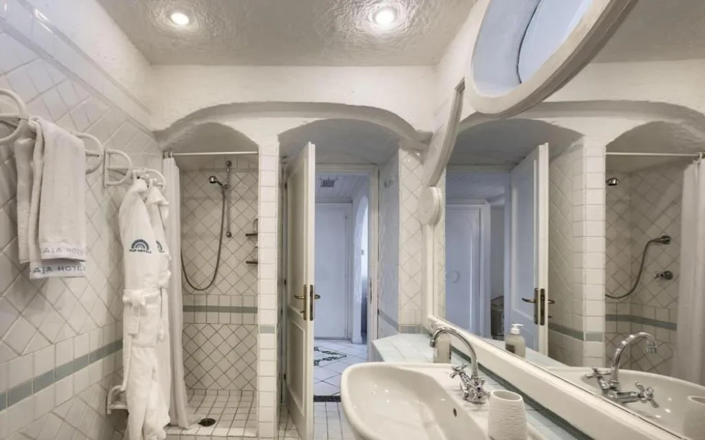 Bagno bianco con doccia e arredi in stile mediterraneo