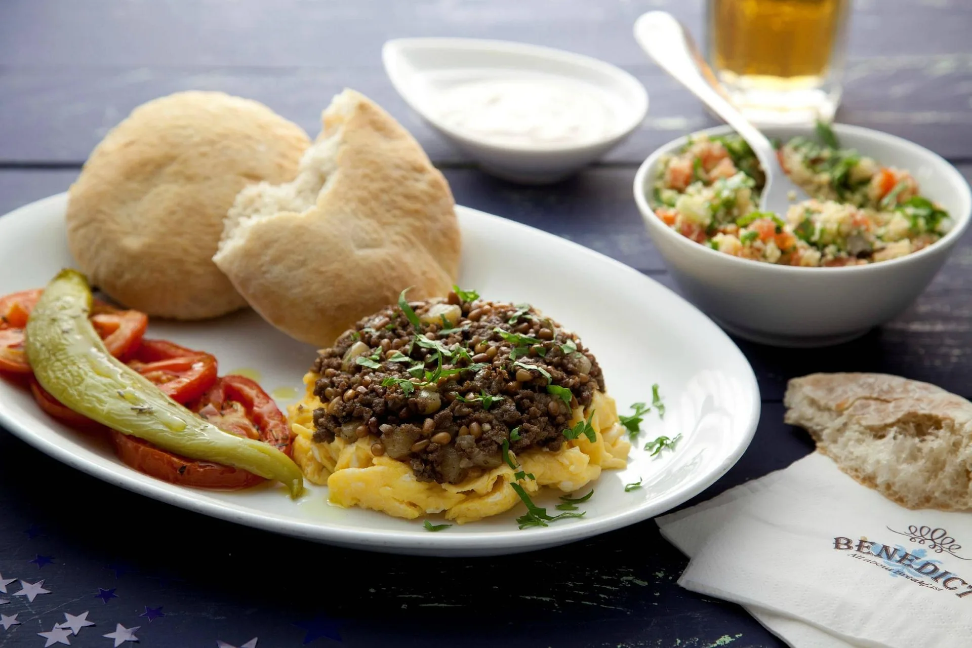 Piatto di uova con carne, pane pita, tabulè e verdure